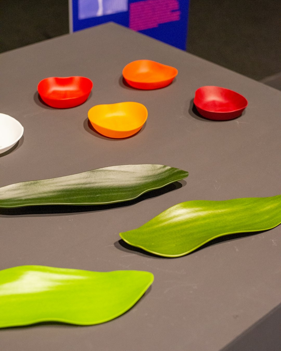 Colorful kidney-shaped and leaf-shaped dishes arranged on a grey surface.