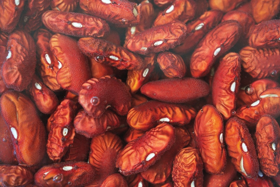 A pile of deep red kidney beans with water droplets.